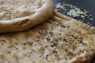 Knoblauch-Koriander-Naan mit Samen, ein schmackhaftes und aromatisches Fladenbrot, das mit Knoblauch, Koriander und knusprigen Samen belegt ist.